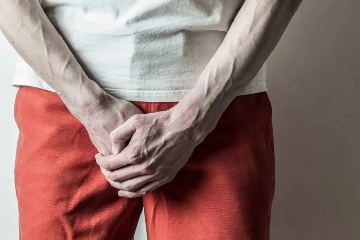 Man holding groin, illustrating discomfort related to Genital Herpes: Symptoms, Transmission & Treatment.