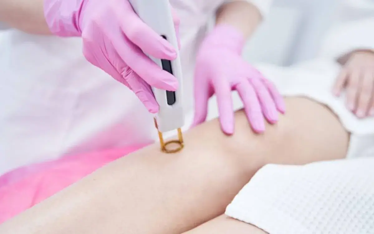 λεπτομέρεια λέιζερ σε γόνατο με ροζ γάντια και λευκό φόντο