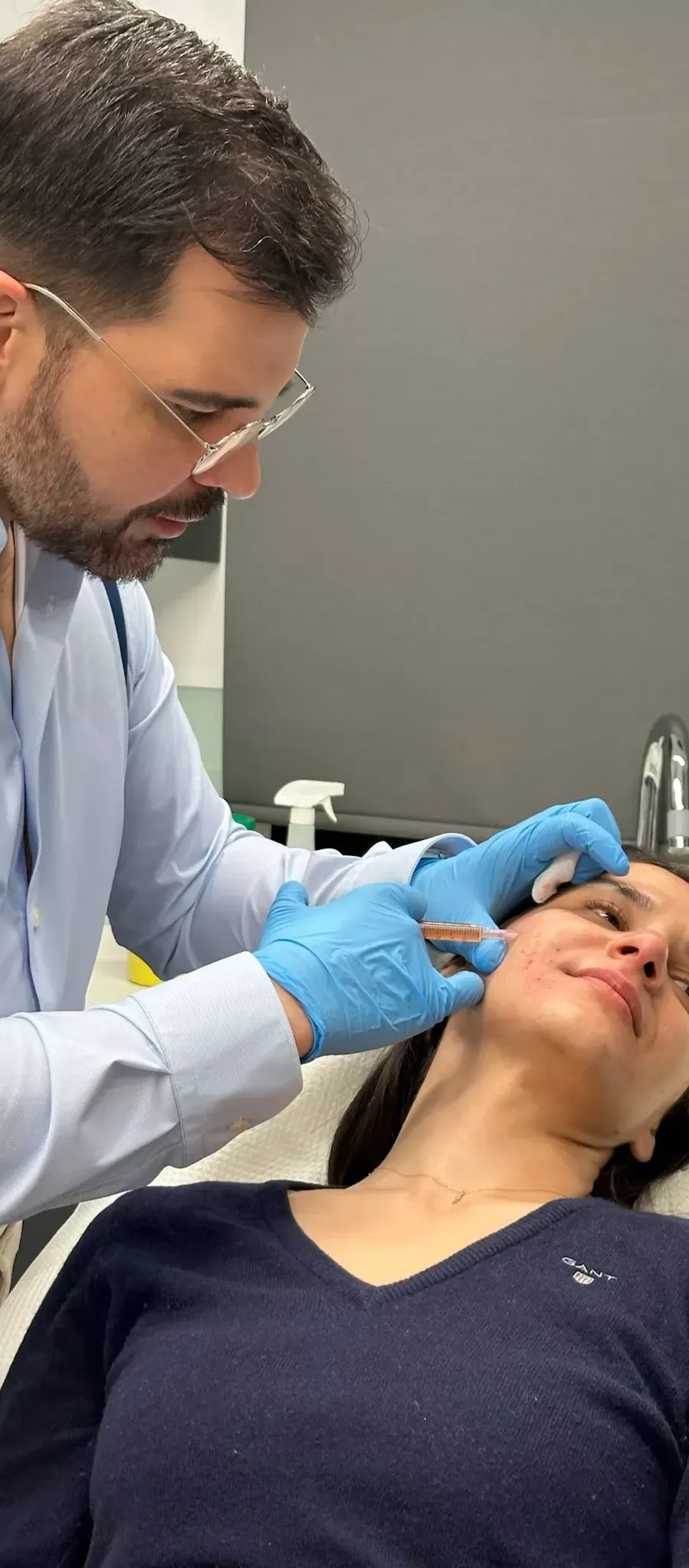 Doctor performing PRP facial treatment on a woman with a syringe.